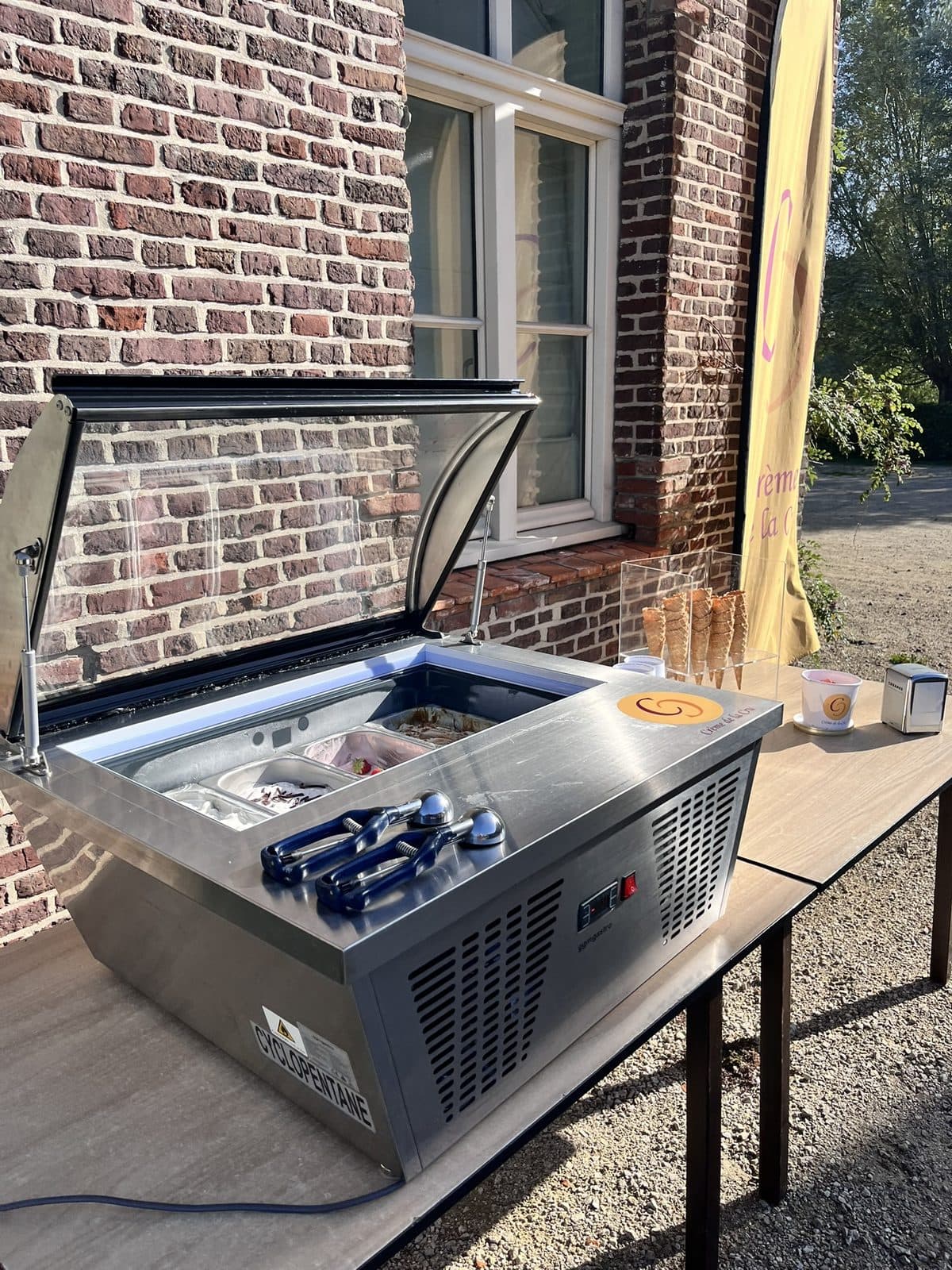 De tafelvitrine opgesteld op een tafel buiten, open en klaar voor gebruik, met hoorntjes en potjes ernaast.